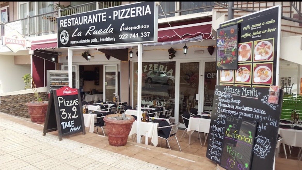 Entrada de Mums Pizza de día con pizarras de menú y terraza