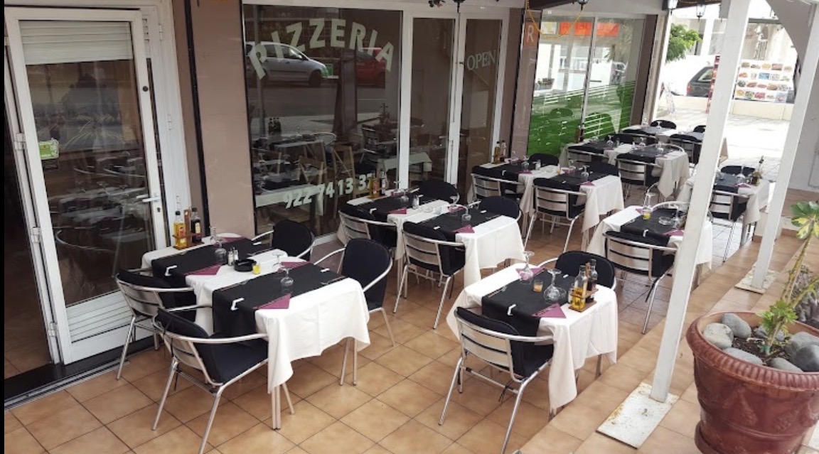 Terraza de Mums Pizza con mesas vestidas de blanco y negro